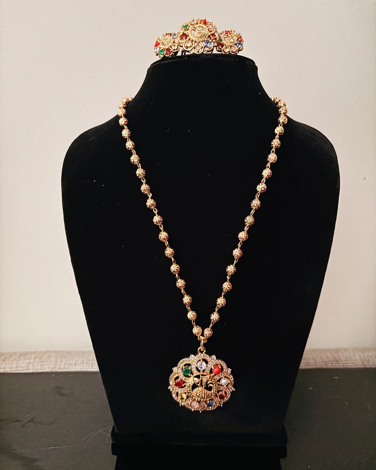 Front view of the long necklace and circular multicolour peacock pendant