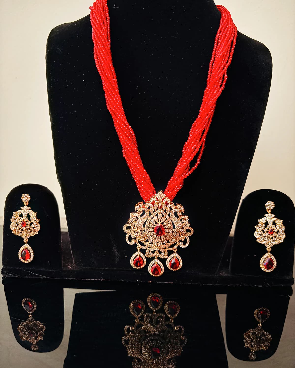 Red bead necklace and earrings arranged on a black velvet display
