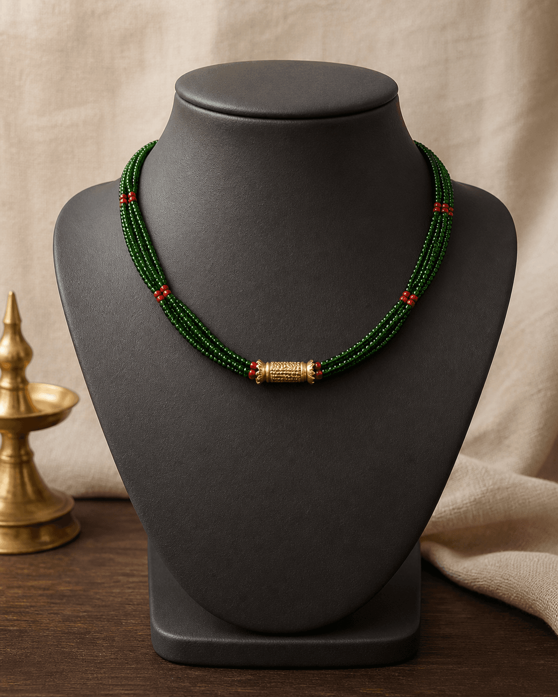 Short Kanchi Tilhari with red and green potey strands and a small gold-plated cylinder