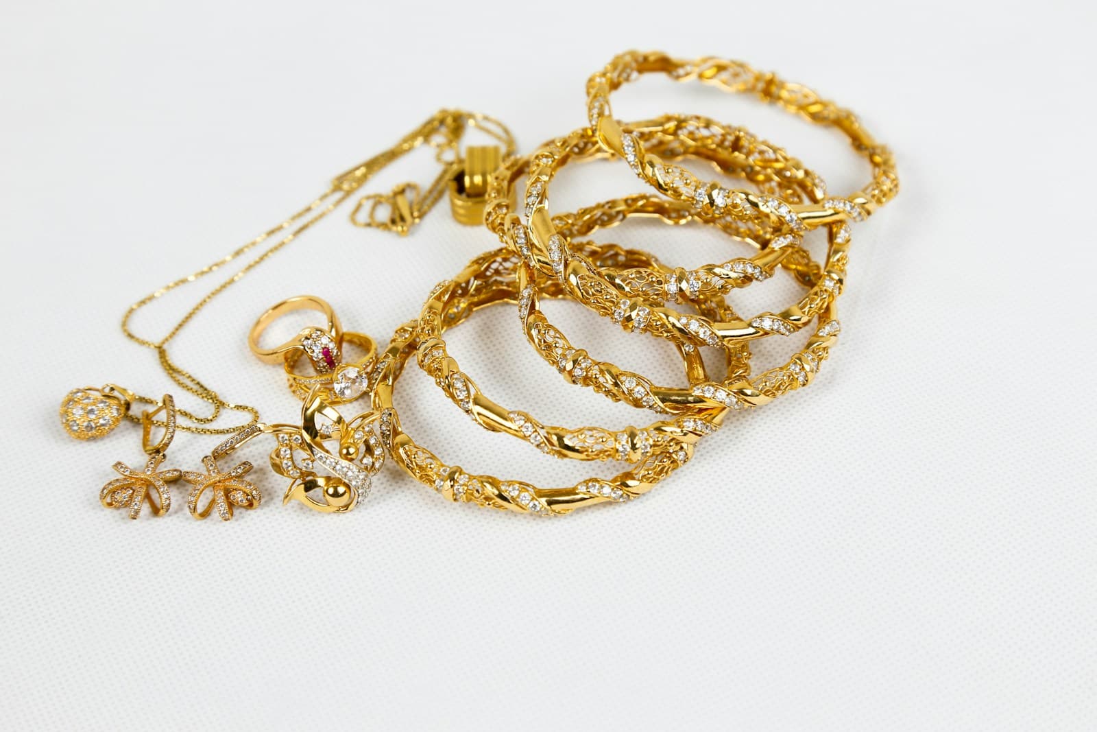 Collection of gold bangles, rings and pendants on a light surface