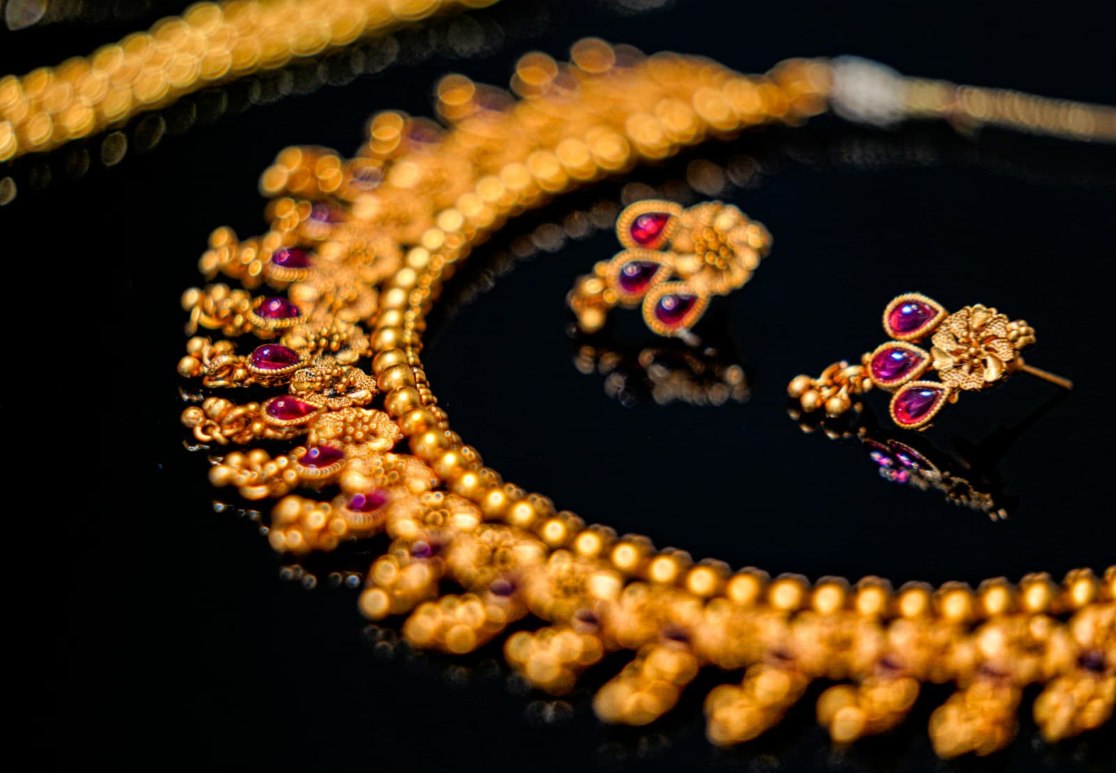 Traditional gold and ruby necklace with matching earrings on black velvet